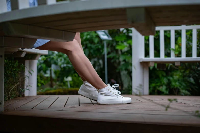 a woman sitting on top of a wooden bench, pexels contest winner, arabesque, wearing white sneakers, juicy legs, upon a peak in darien, dynamic angled shot