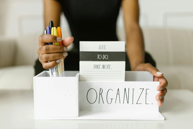 a woman is holding a pen in a box, by Julia Pishtar, pexels, woman holding sign, clean and organized, stacked image, on a white table