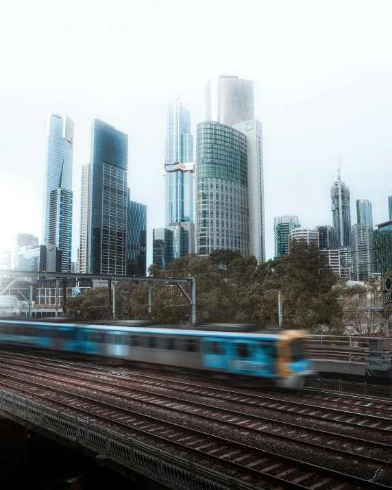 a train traveling through a city next to tall buildings, by Liza Donnelly, unsplash contest winner, melbourne, trans rights, background image, koyaanisqatsi