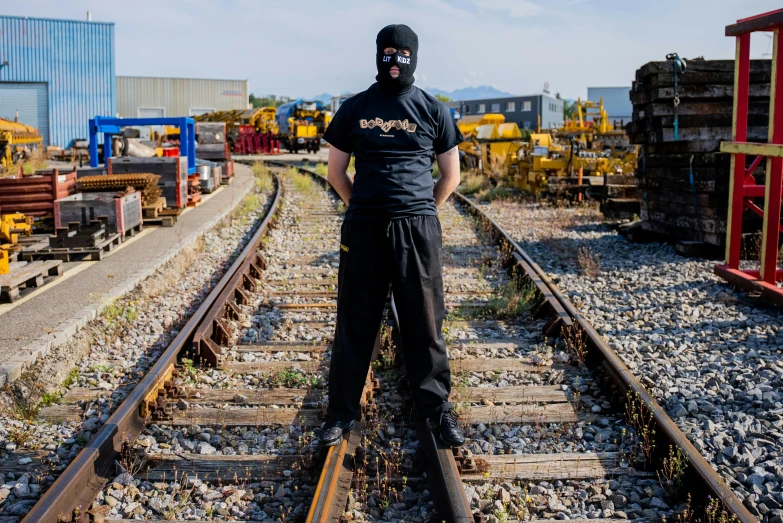 a man wearing a mask standing on a train track, a portrait, reddit, mechanic punk outfit, official store photo, mk ninja, cybertech wear