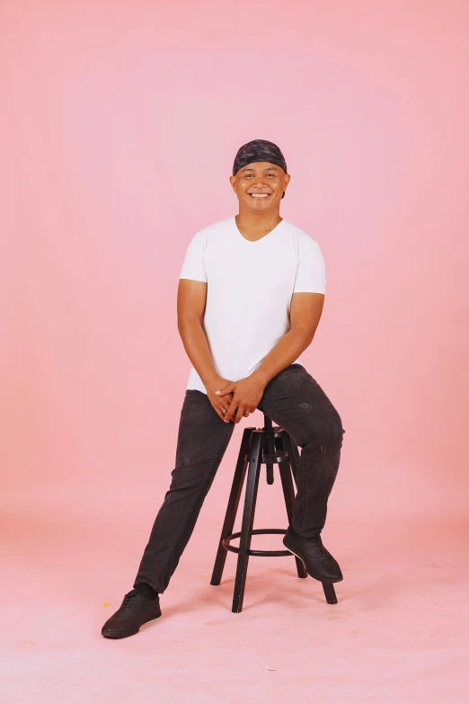 the man is posing for the camera while sitting on a stool