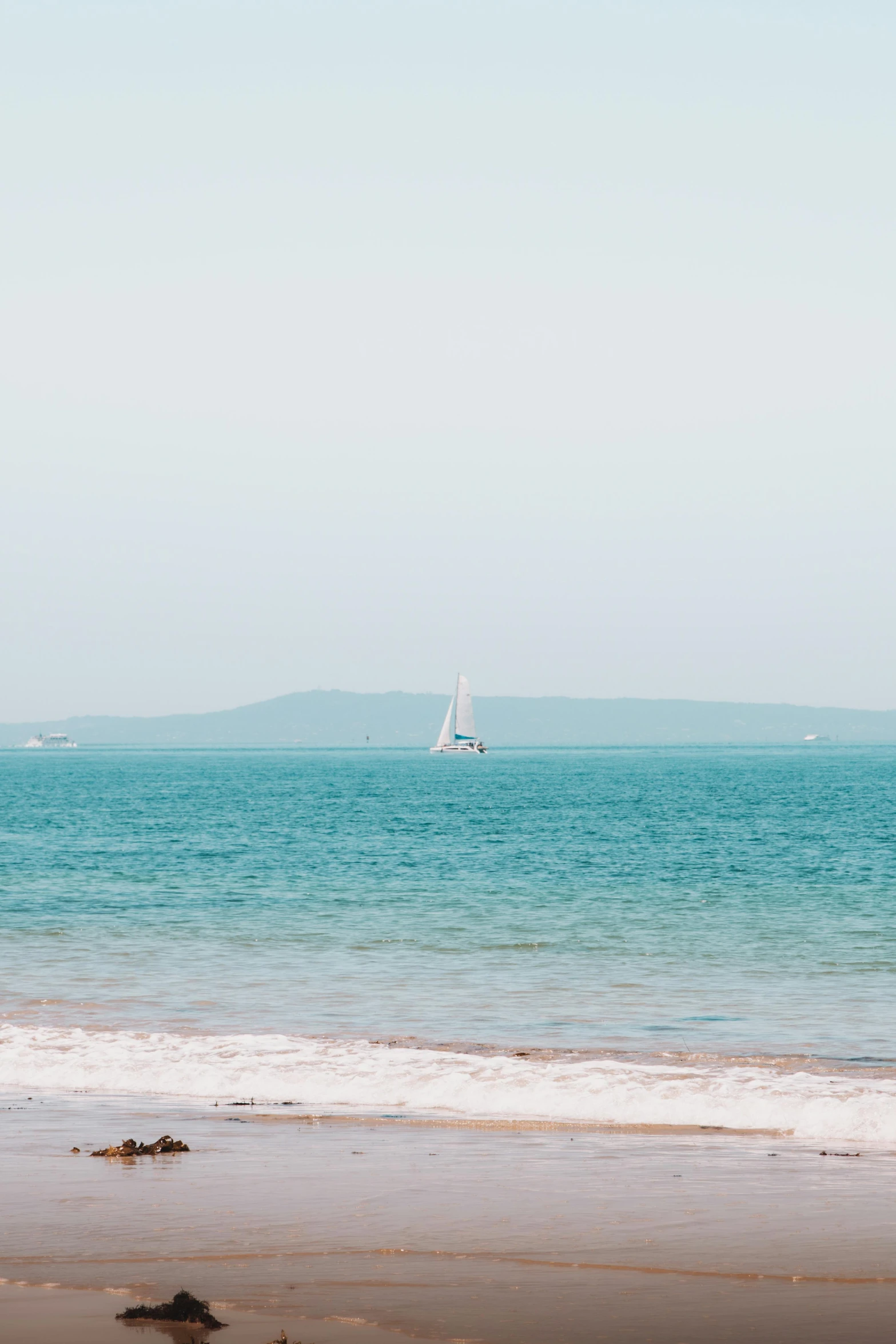 a sailboat sitting out on a calm day by the ocean