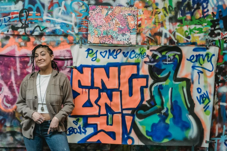 a woman standing in front of a wall covered in graffiti, art student, background image, sidney lugo, group photo