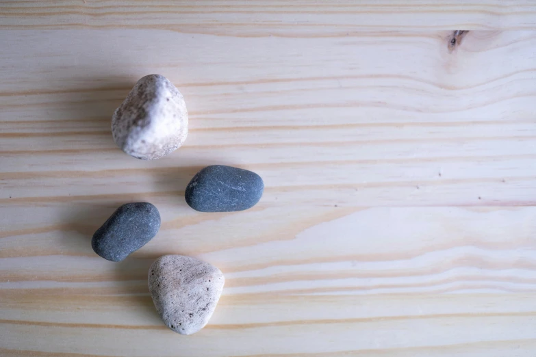 a group of rocks sitting on top of a wooden table, unsplash, minimalism, background image, pochi iida, close-up product photo, limbs