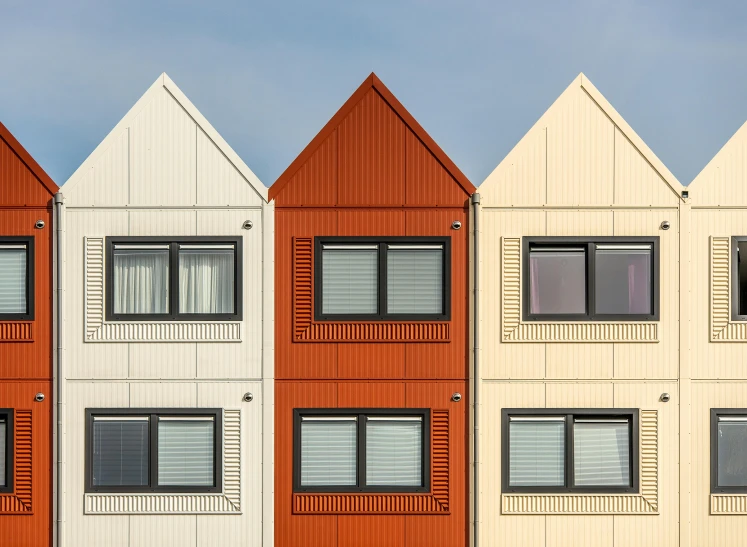 a row of multi - colored houses in front of a blue sky, a digital rendering, by Tobias Stimmer, trending on unsplash, modular constructivism, white and orange, metal panels, shipping containers, red brown and grey color scheme