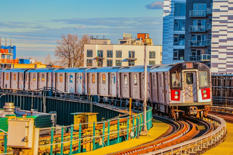 a train traveling through a city next to tall buildings, by Carey Morris, shutterstock, mta subway entrance, all buildings on bridge, 🚿🗝📝