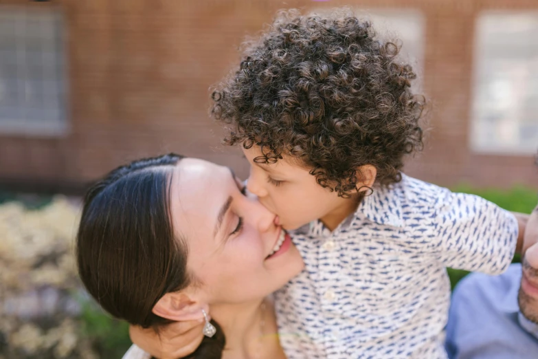 a woman holding a small child in her arms, pexels contest winner, brown curly hair, boy has short black hair, profile image, tongue out