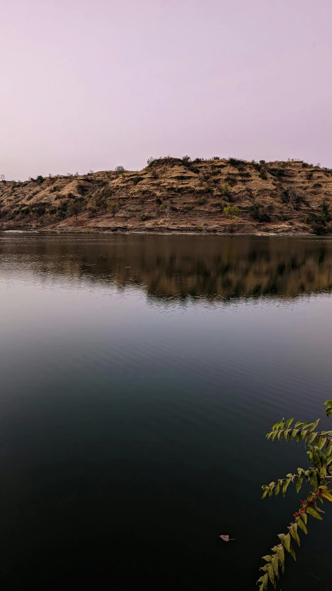 a body of water with a hill in the background, by Saurabh Jethani, samikshavad, low quality photo, panoramic, fan favorite, faded glow