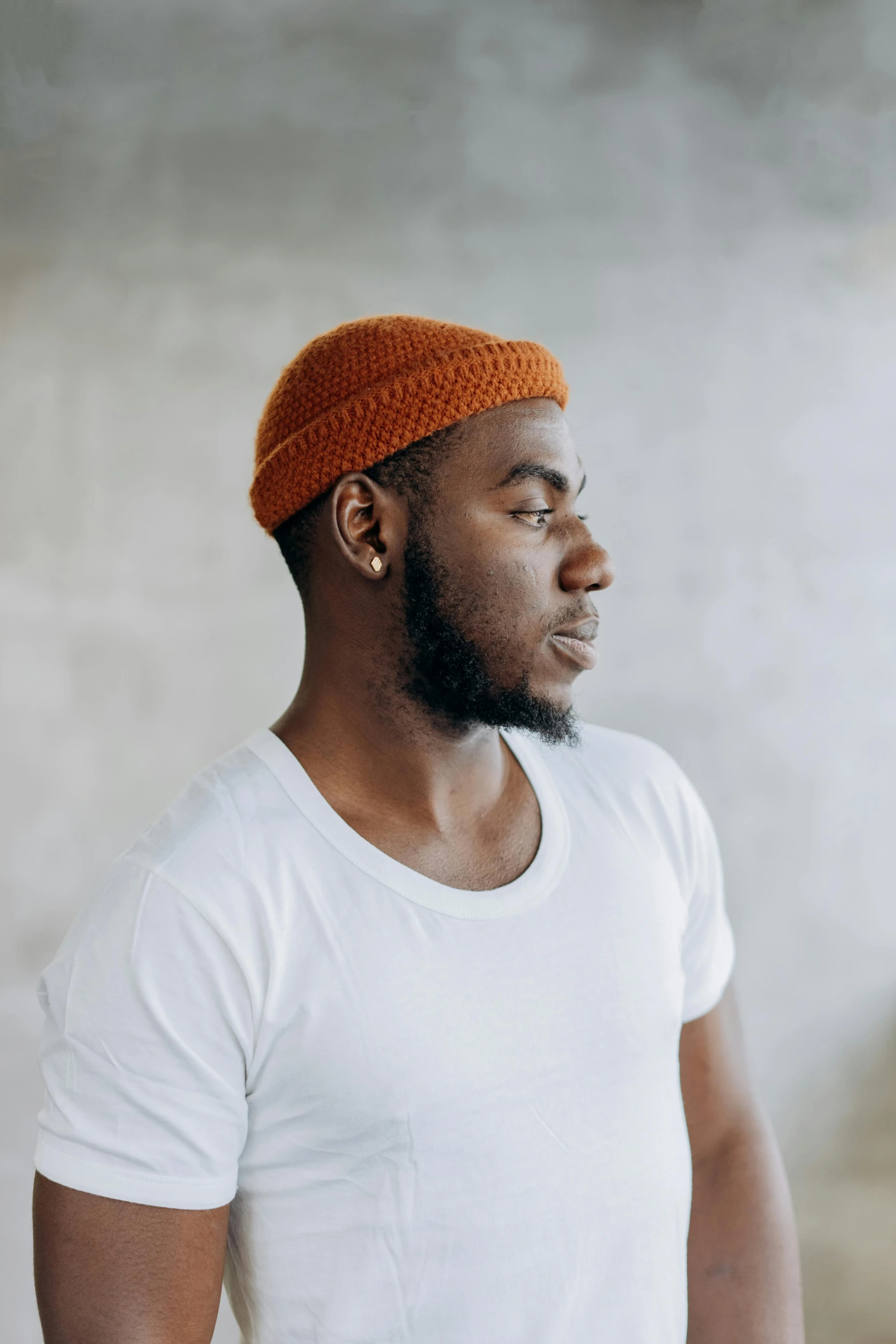 a black man in a white t - shirt is wearing a orange beret