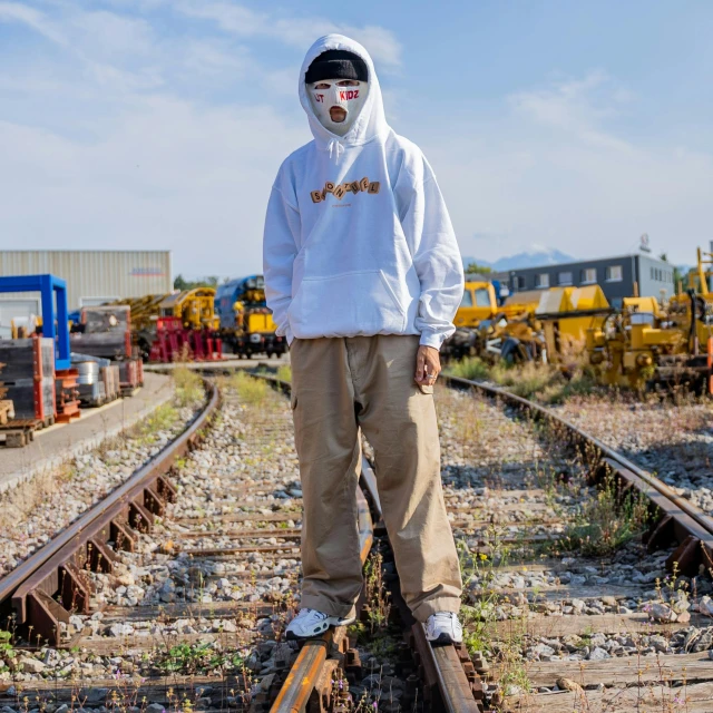 a man in a white hoodie standing on a train track, japanese streetwear, official store photo, poop, 15081959 21121991 01012000 4k