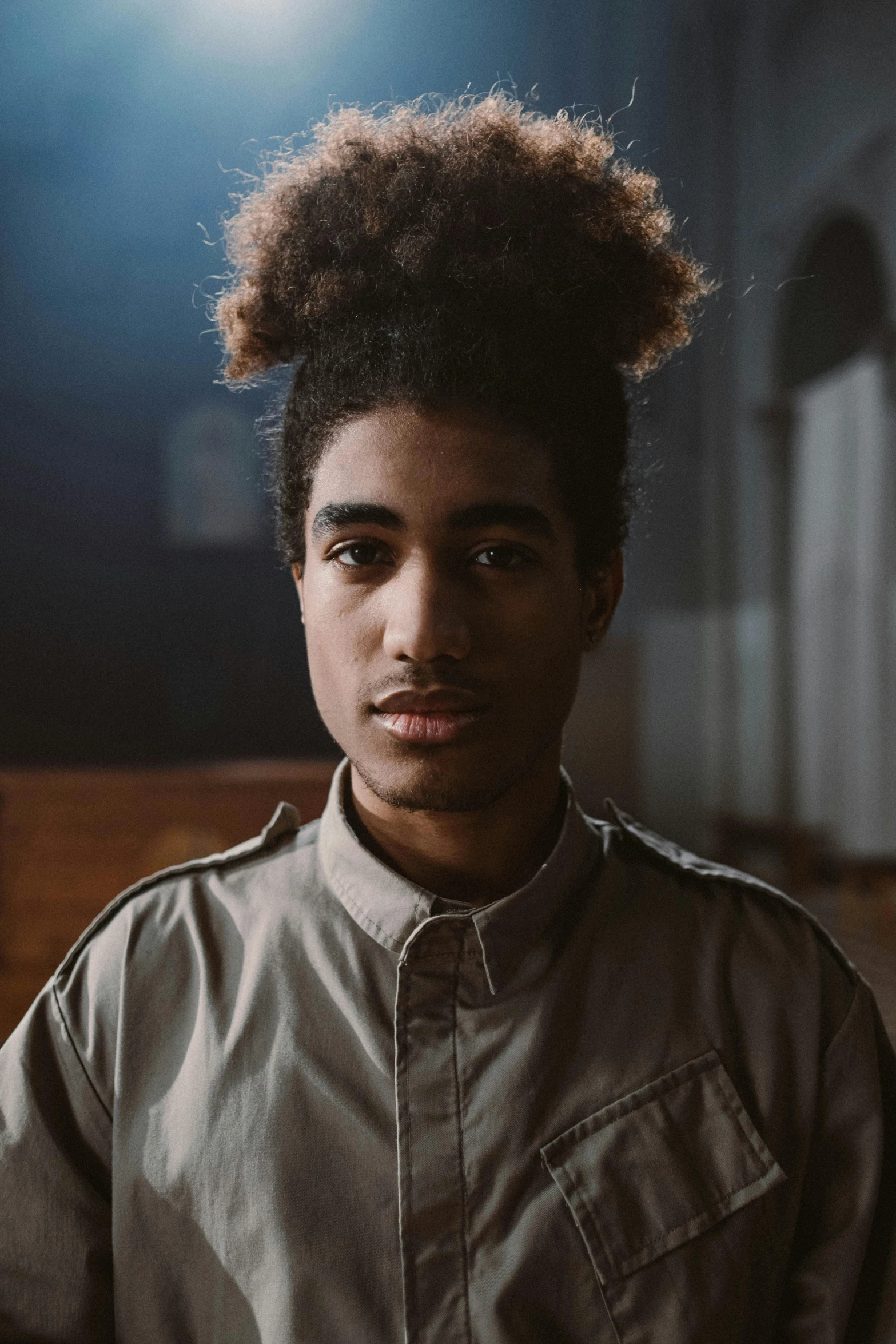 a young man with a long top knot has an afro in his hair