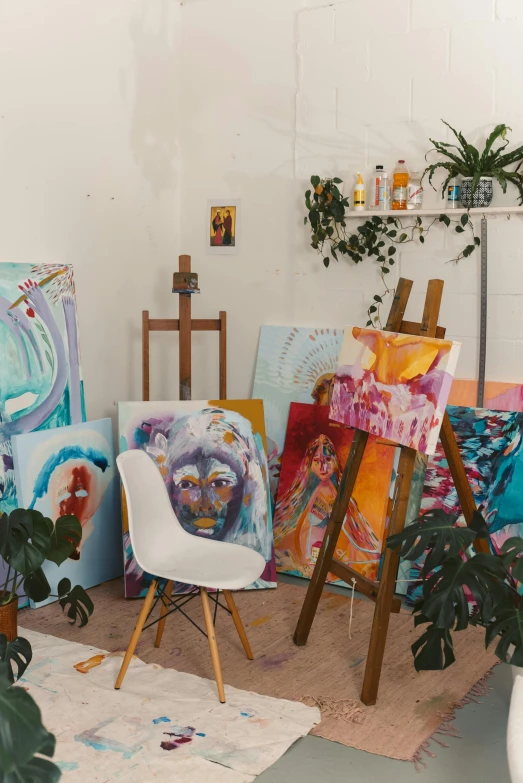 a room filled with lots of art and plants, a painting, inspired by artist, trending on pexels, process art, easel, white studio, multicoloured, canvas