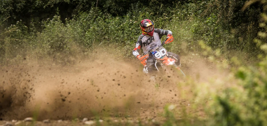 a person on an orange motorcycle rides through dirt