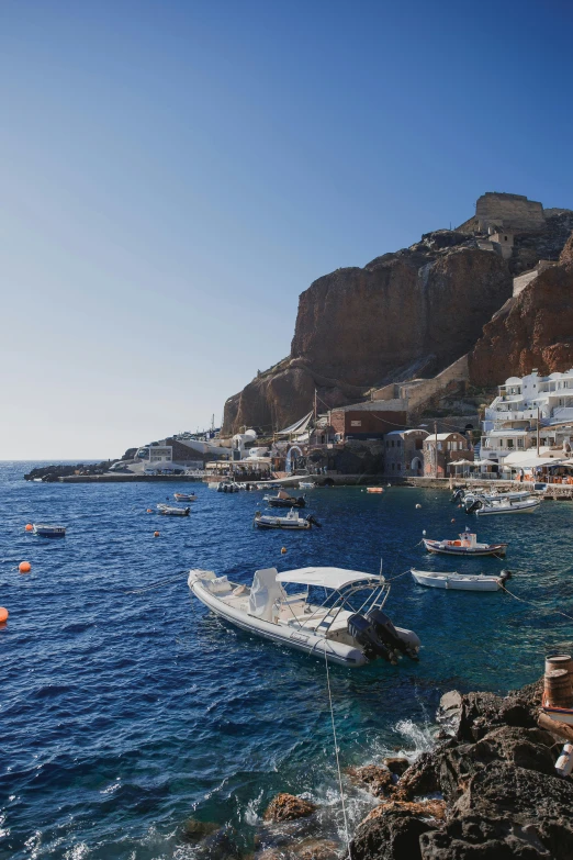 some boats floating in the water near a rocky shore