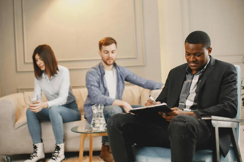 a group of people sitting on a couch in a living room, black man, psychology, sat in an office, in the center of the image