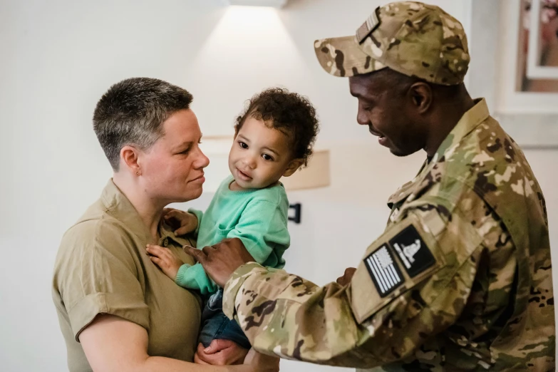 a soldier holds a small child in his arms, pexels contest winner, woman holding another woman, avatar image, healthcare, lgbt