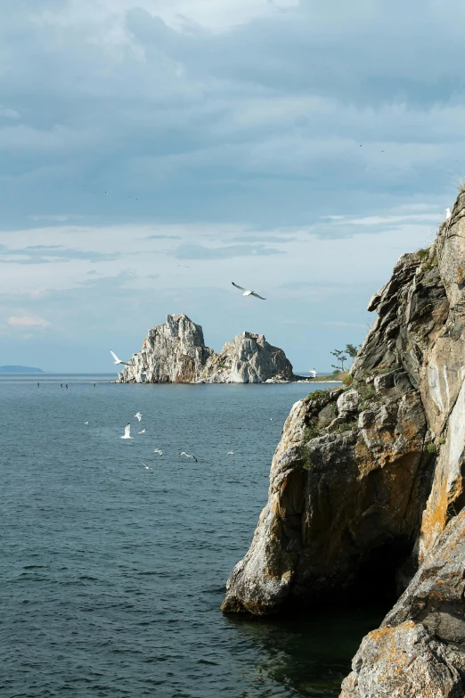 a man standing on top of a cliff next to a body of water, by Okada Hanko, gigapixel photo, slide show, south korea, rock formations