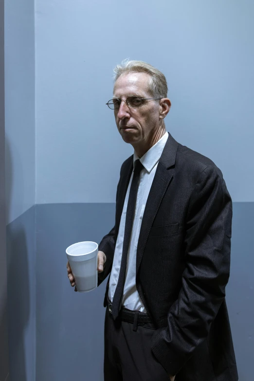 a man in a suit holding a cup of coffee, an album cover, by David Begbie, trending on reddit, photorealism, william gibson, group of people in an elevator, photograph credit: ap, nicholas cage