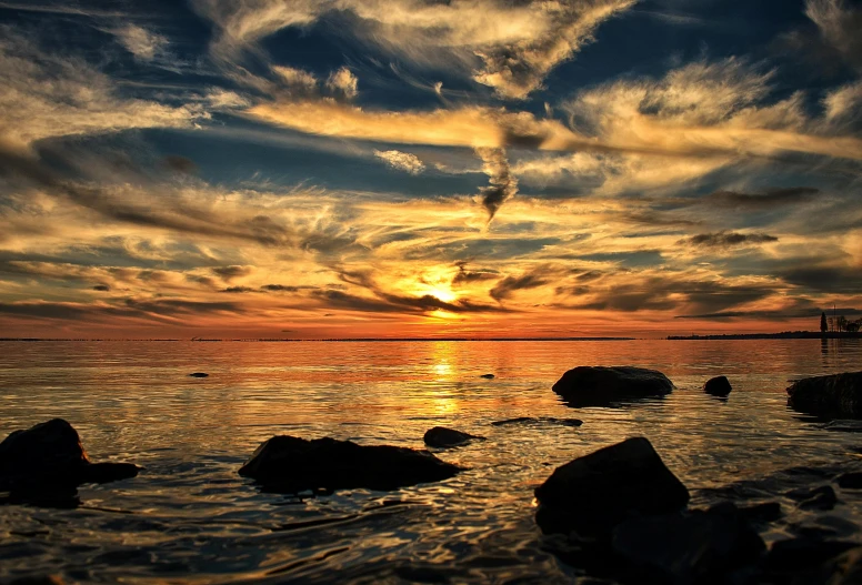 a sunset over a body of water with rocks in the foreground, by Jesper Knudsen, pexels contest winner, thumbnail, sunset clouds, archipelago, liquid gold