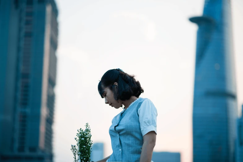 a woman standing on top of a roof holding a plant, inspired by Cheng Jiasui, unsplash, realism, side profile shot, late summer evening, still from a live action movie, japanesse farmer