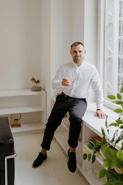 a man in formal clothing is sitting on a bench near the window