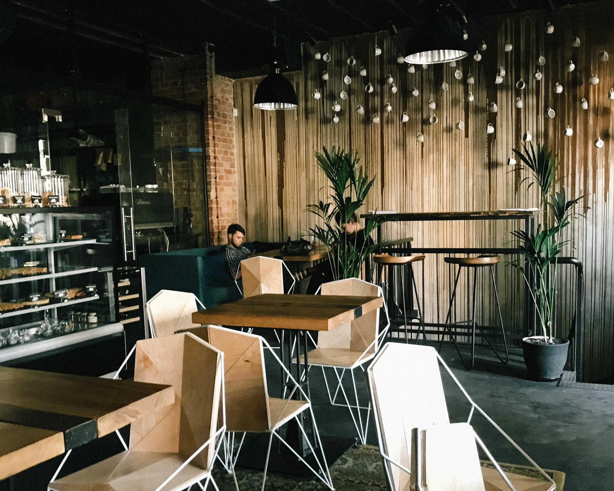 a man sitting at a table in a coffee shop, by Robbie Trevino, light and space, empty stools, “ iron bark, millennial vibes, bakery