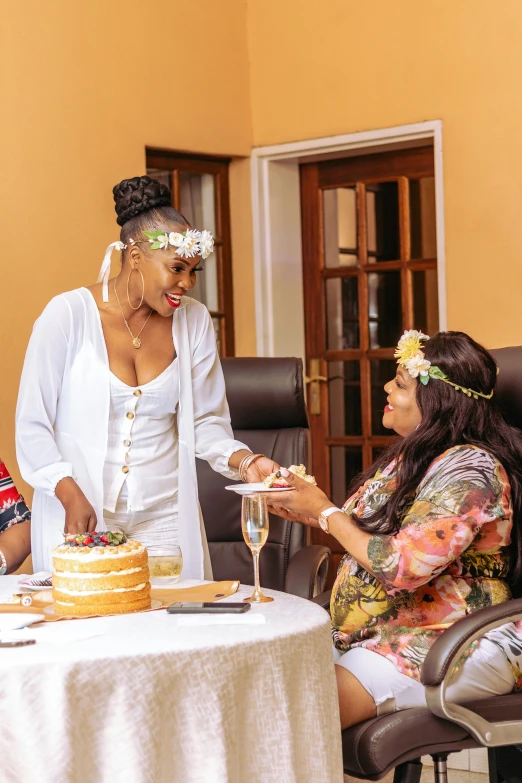 two woman at a table that have two cake on top