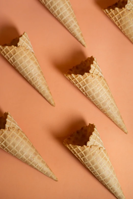 a group of ice cream cones sitting on top of a pink surface, pale orange colors, thumbnail, uncrop, image