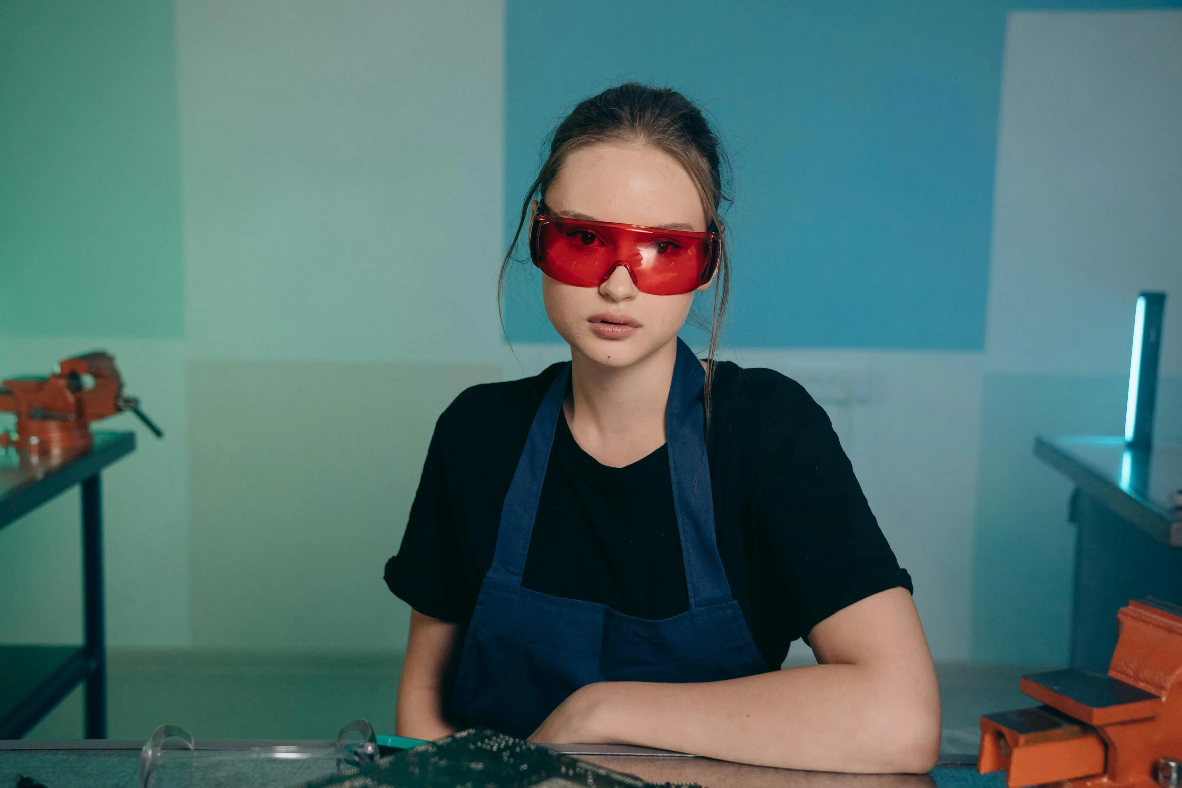 a woman sitting at a table with a pair of red glasses on her face, inspired by Elsa Bleda, trending on pexels, process art, stood in a lab, girl wearing uniform, coloured gel studio light, plating