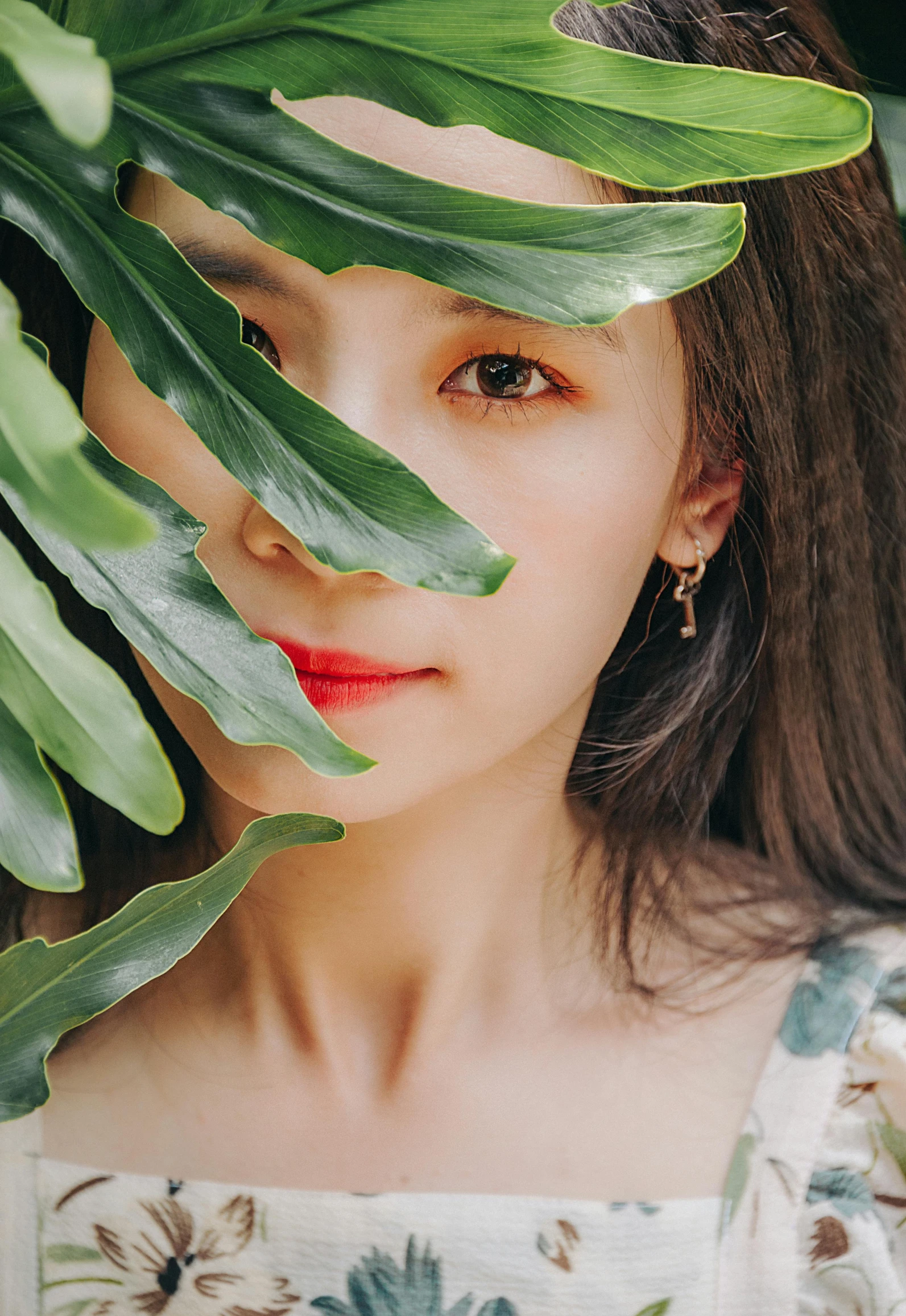 a woman holding a green leaf in front of her face, a picture, inspired by Jung Park, trending on pexels, realism, thin round earrings, ulzzang, ✨🕌🌙, official store photo