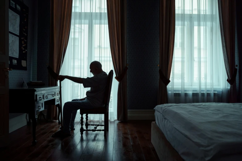 a man sitting in a chair in front of a window, by Elsa Bleda, pexels contest winner, hurufiyya, sitting on a bed, dementia, inside a grand, ( ( theatrical ) )