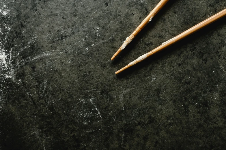 a pair of chopsticks sitting on top of a table, inspired by Inshō Dōmoto, unsplash, minimalism, chalk texture on canvas, blackboard, well worn, lacquered