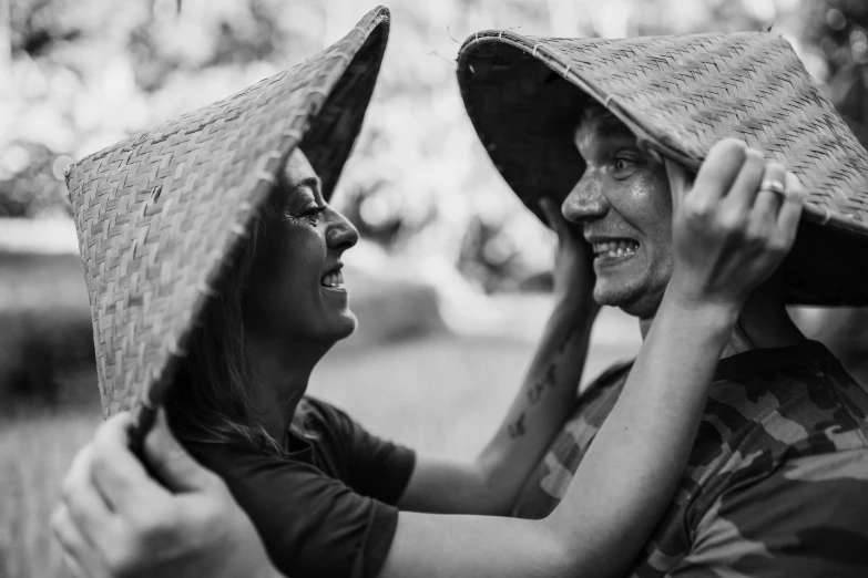 a black and white photo of a man and a woman, by Emma Andijewska, pexels contest winner, wearing straw hat, playful smile, vietnamese woman, avatar image