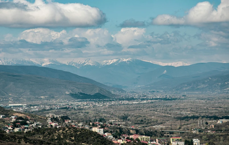 the city below the mountains with snow capped mountain peaks