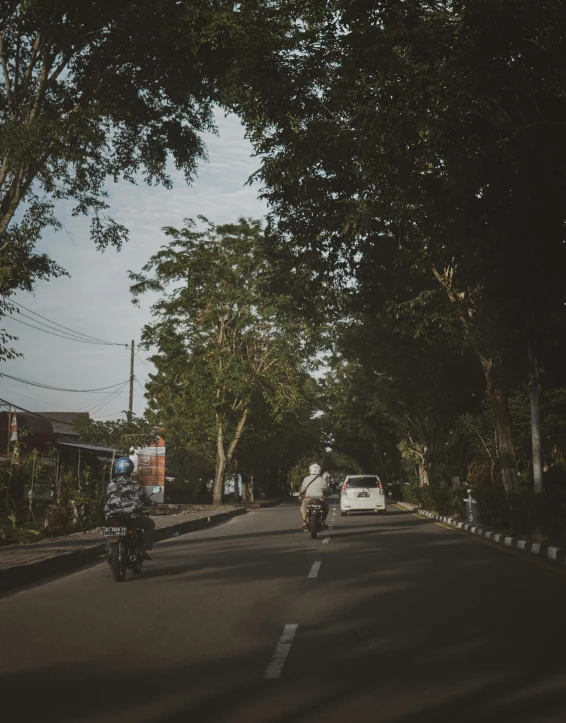 two people on motor bikes riding down the street