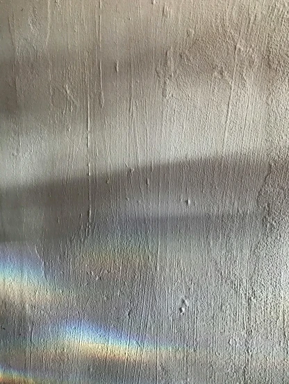 a close up of a metal plate with a rainbow on it, a photorealistic painting, inspired by Lucio Fontana, unsplash, light and space, walls are made of dry wall, faded!! very soft lights, shot with iphone 1 0, afternoon sunlight