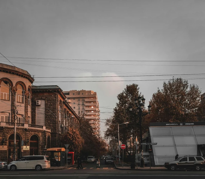 a street filled with lots of traffic next to tall buildings, a photo, by andrei riabovitchev, pexels contest winner, realism, dieselpunk volgograd, early morning mood, north melbourne street, grey