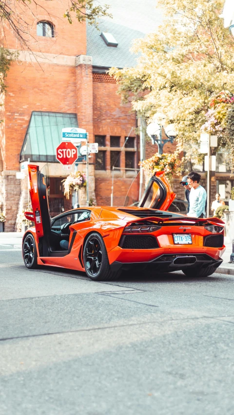 an orange sports car sits parked on the street in front of a stop sign