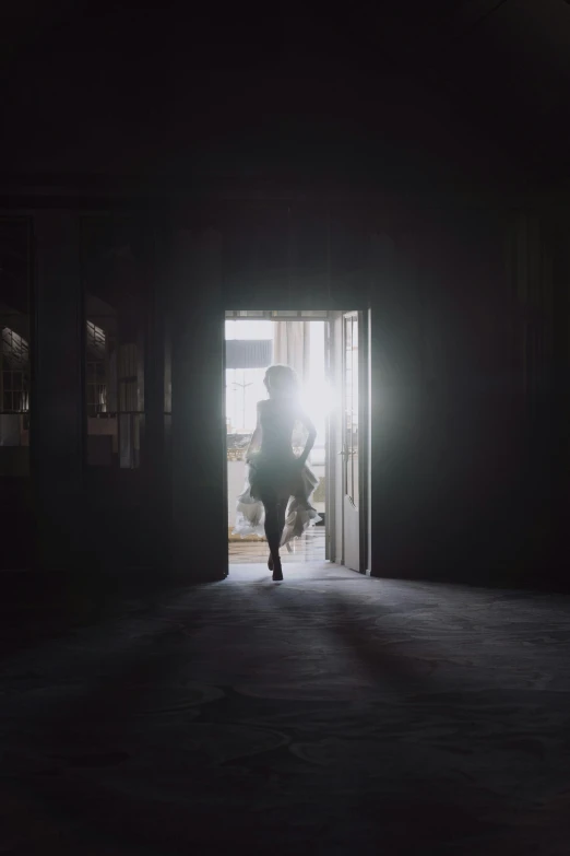 a person walking through an open door in a dark room, inspired by Gregory Crewdson, pexels contest winner, light and space, girl running, lens flares. cinematic, ballerina, in a warehouse