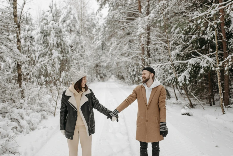 the young couple is walking hand in hand on a snowy path