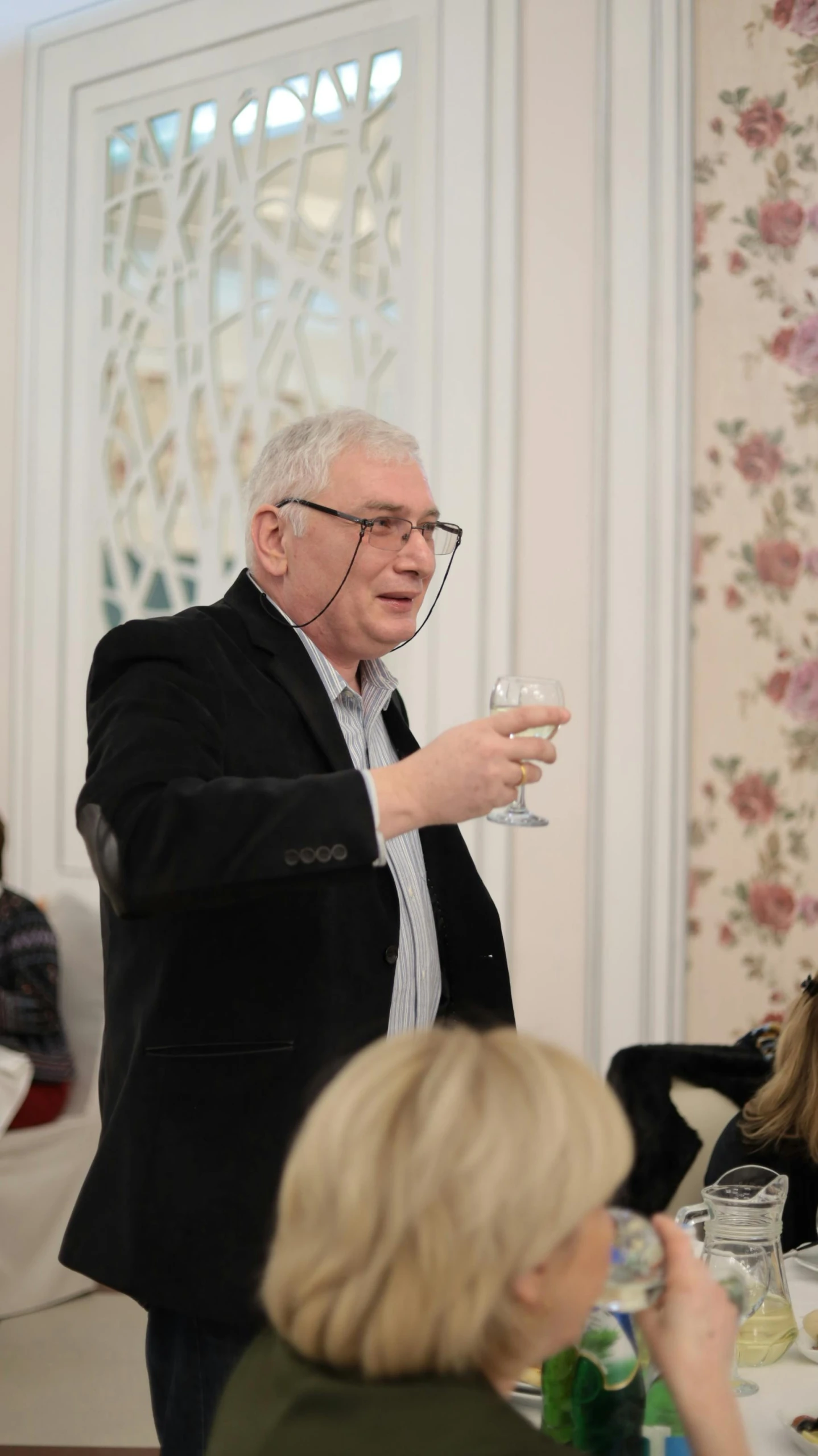 a man standing in front of a group of people, holding a glass of wine, academician prokhor zakharov, tv show, facing to audience