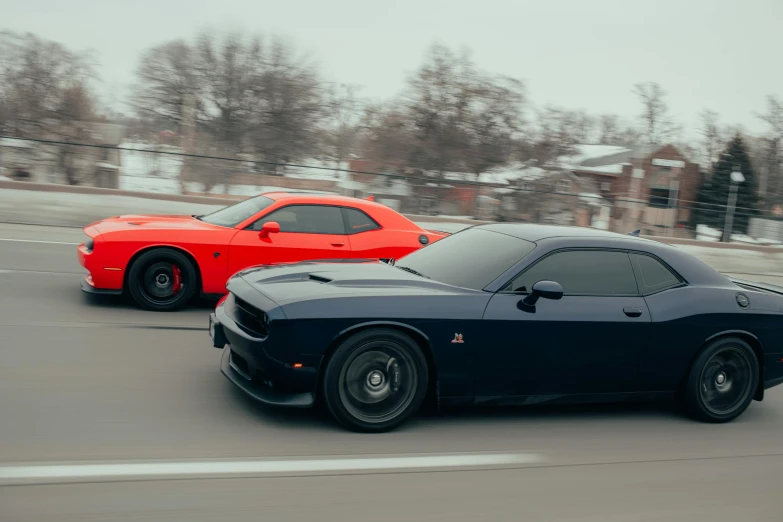 two black and red muscle cars on the highway