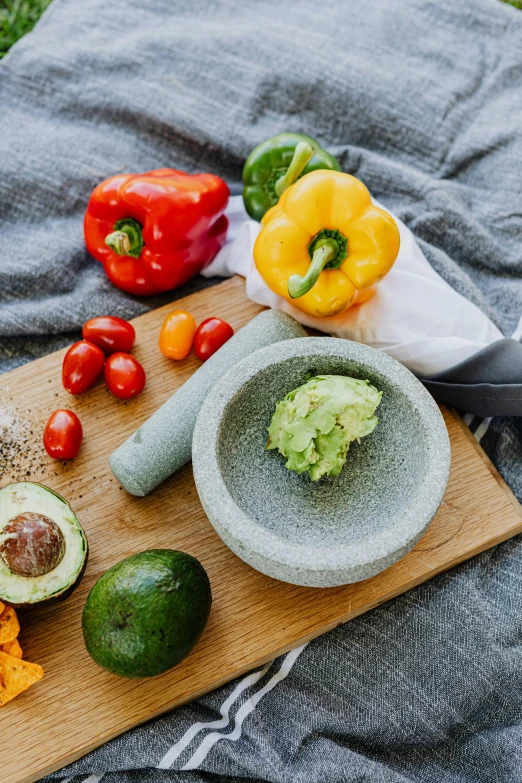 a wooden cutting board topped with a bowl of guacamole, a still life, inspired by Ceferí Olivé, unsplash, pepper, multicoloured, smooth solid concrete, detailed product image