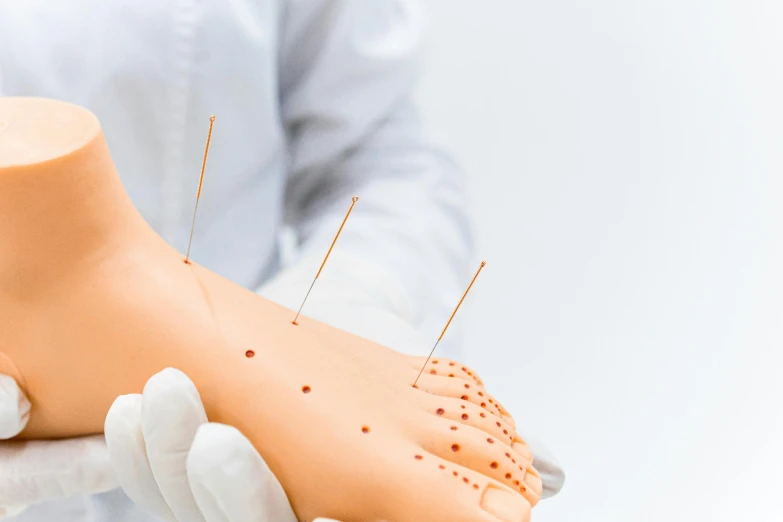 a close up of a person holding a dummy, a colorized photo, by Dan Content, shutterstock, acupuncture treatment, needles, where a large, straya