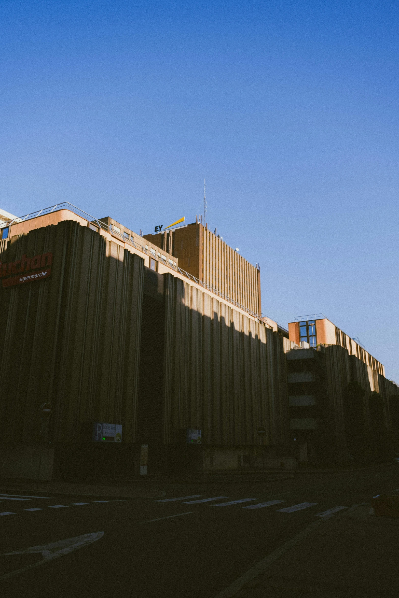 a tall building sitting on the side of a road, by Jan Tengnagel, unsplash, brutalism, golden sunlight, aardman studios, warehouses, brown