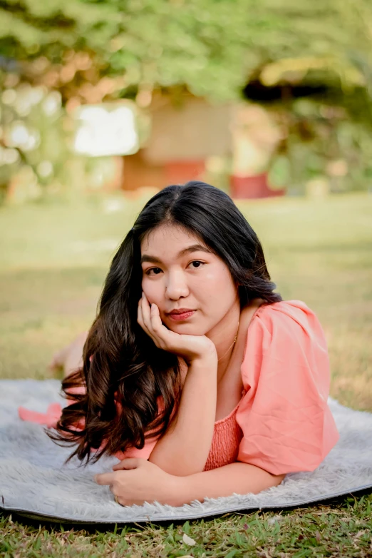 a beautiful woman laying on the grass while posing for the camera