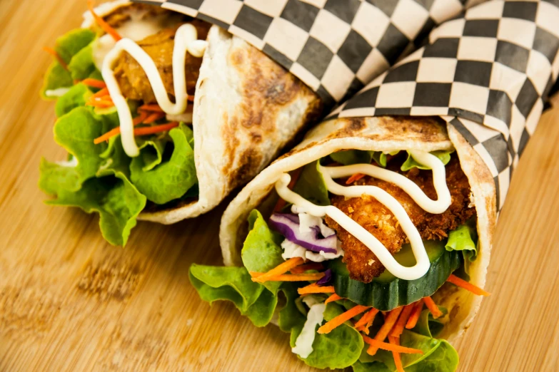 a couple of burritos sitting on top of a wooden table, by Joe Bowler, shutterstock, chequered cape, sandwich with fried tofu, square, greens)