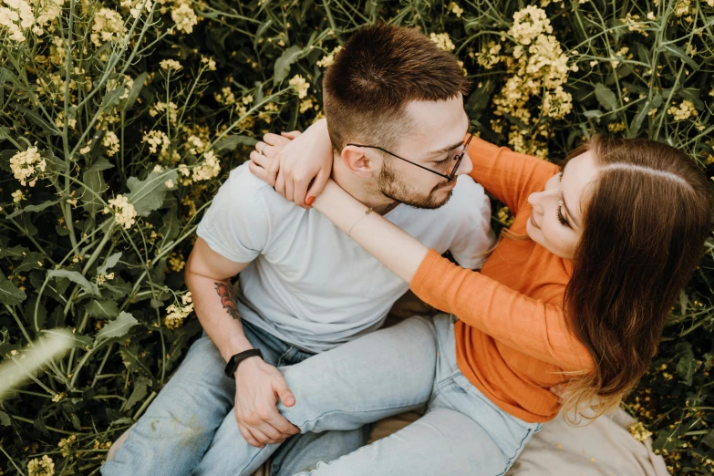 a woman sitting next to a man on top of a grass covered field