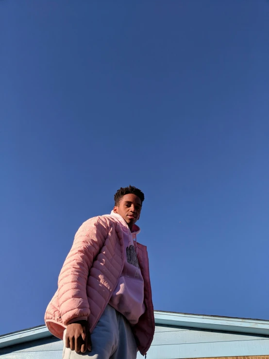 a man standing on a sidewalk wearing a pink jacket