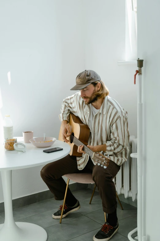 a man sitting at a table with an acoustic guitar